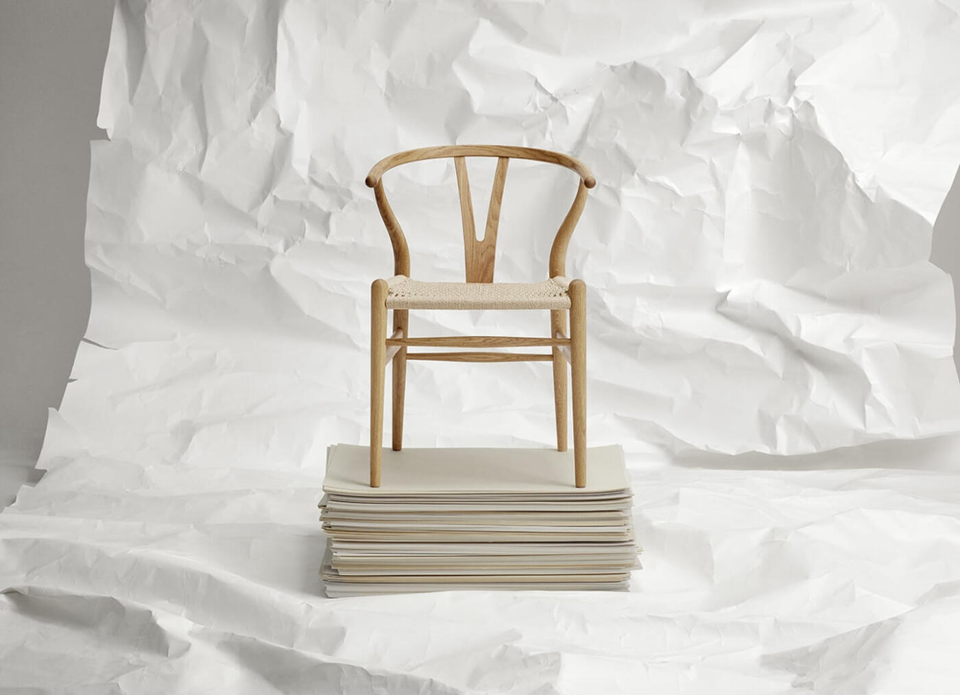 Krzesło drewniane na stosie białych kartek, minimalistyczny design.
