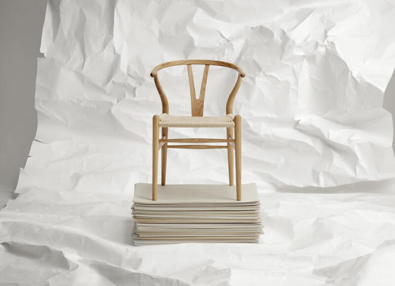 Krzesło drewniane na stosie białych kartek, minimalistyczny design.