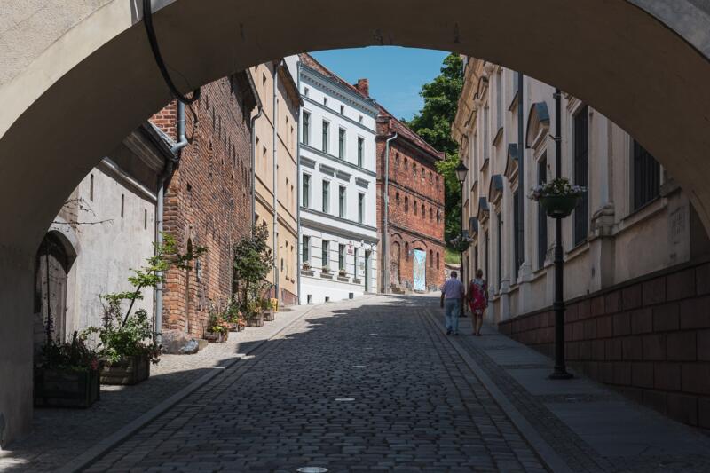Urokliwa uliczka z zabytkowymi kamienicami w słońcu.