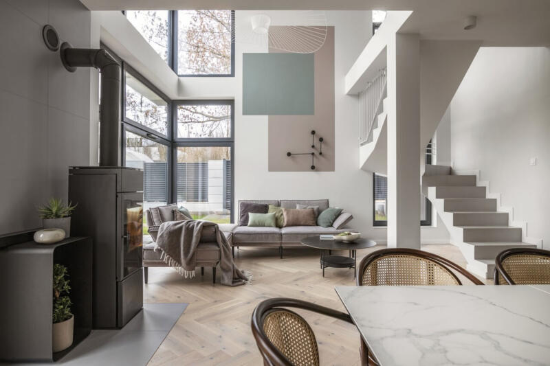 Nowoczesny salon z dużymi oknami i eleganckim kominkiem.