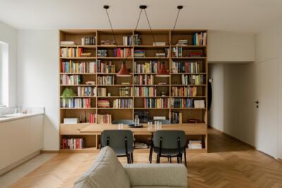 Stylowa biblioteka z drewnianymi półkami i nowoczesnym oświetleniem.