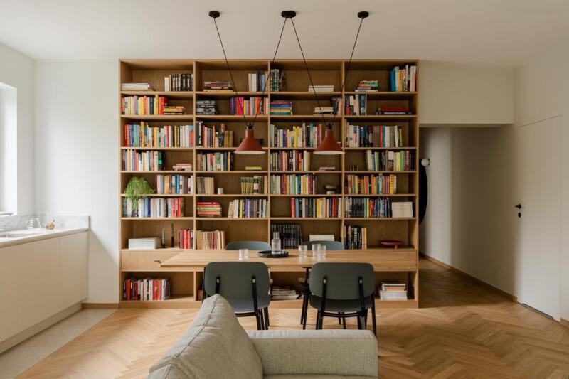 Stylowa biblioteka z drewnianymi półkami i nowoczesnym oświetleniem.
