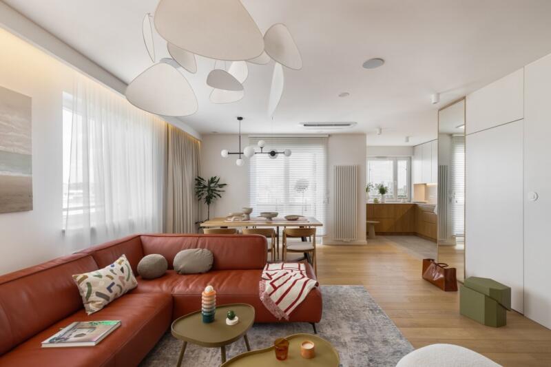 Nowoczesny salon z brązową kanapą i designerskim oświetleniem.