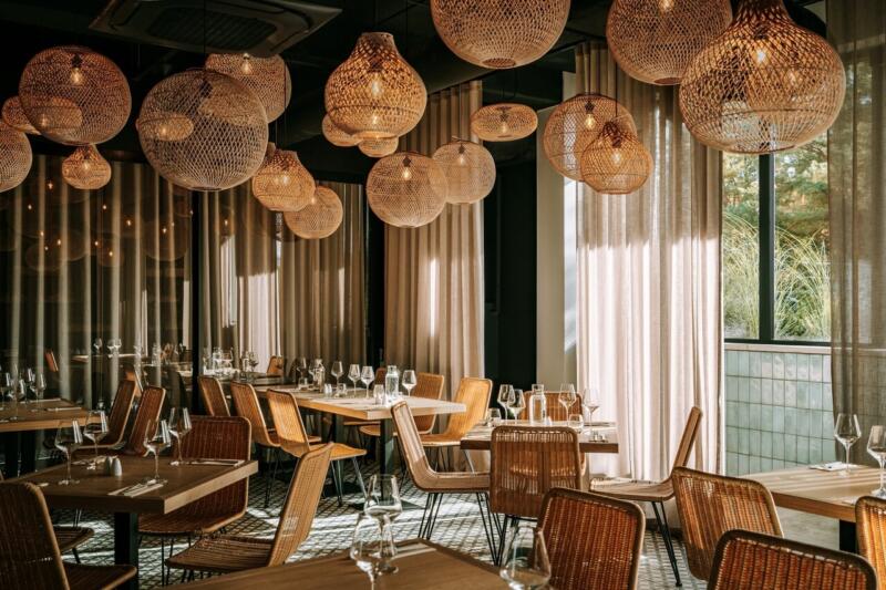 Stylowa restauracja z rattanowymi lampami i drewnianymi krzesłami.