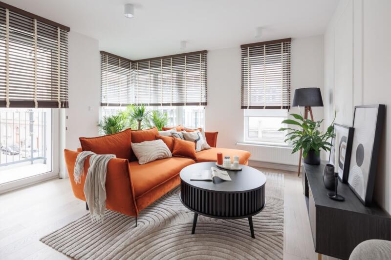 Nowoczesne wnętrze z pomarańczową sofą i designerskimi dodatkami.
