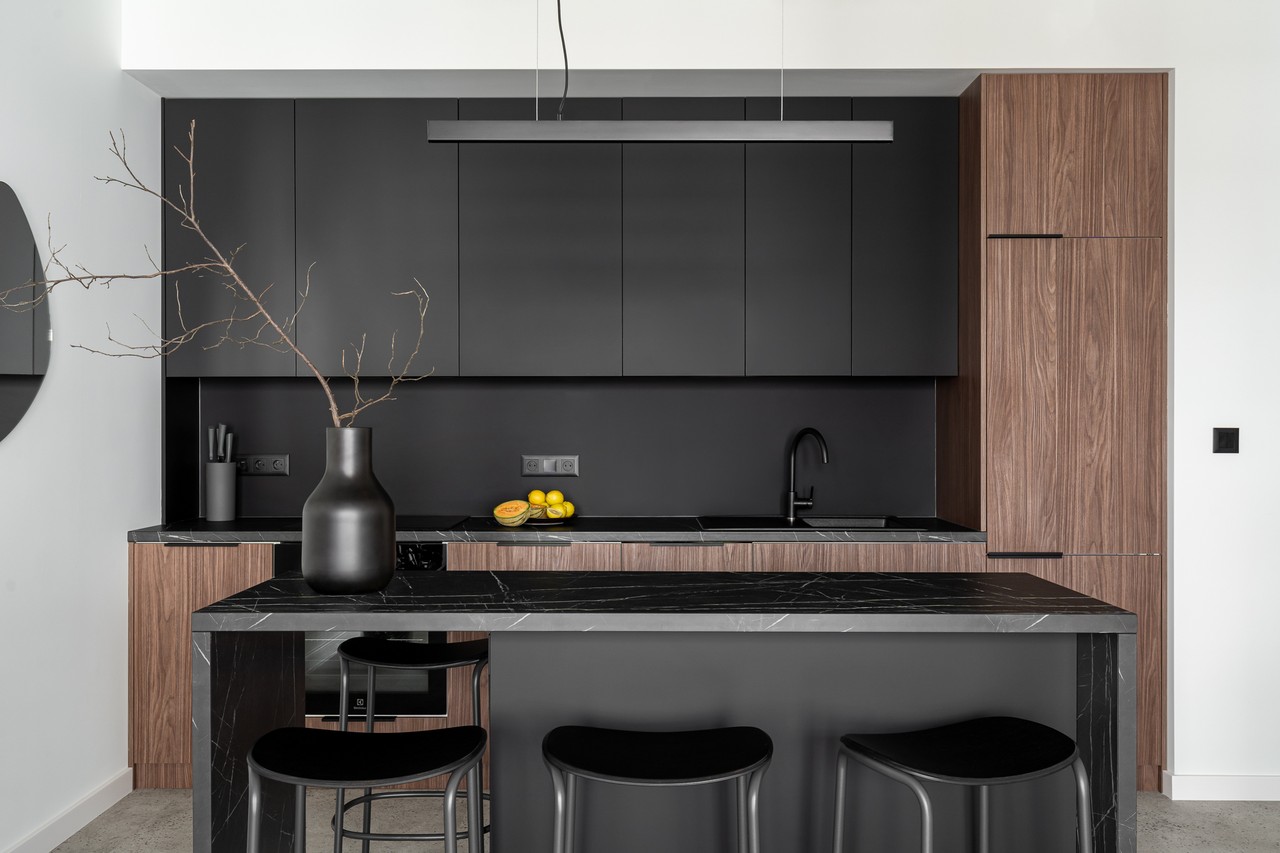 Modern kitchen with black cabinets and wooden accents.