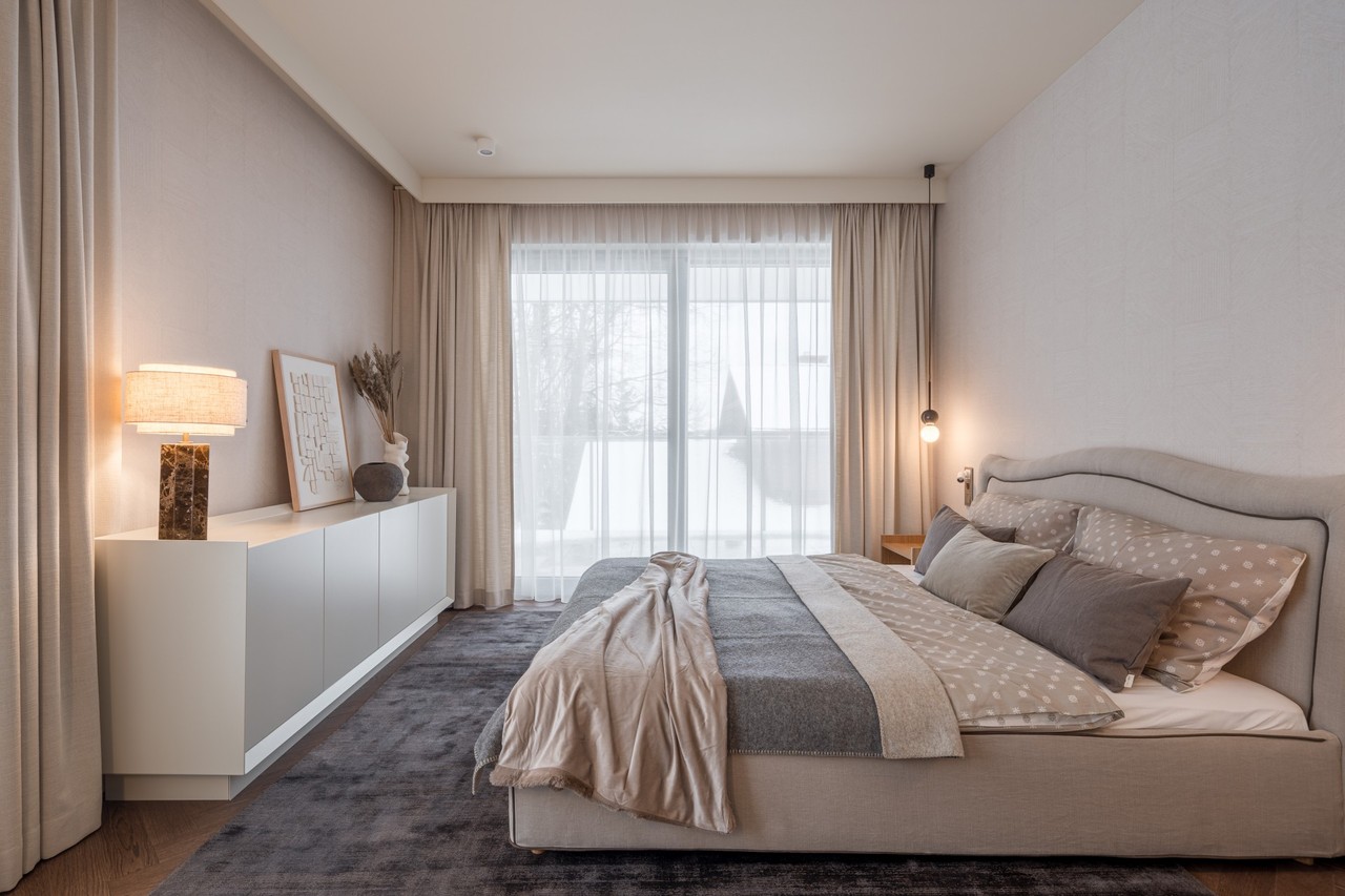 An elegant bedroom with beige curtains and a stylish table lamp.