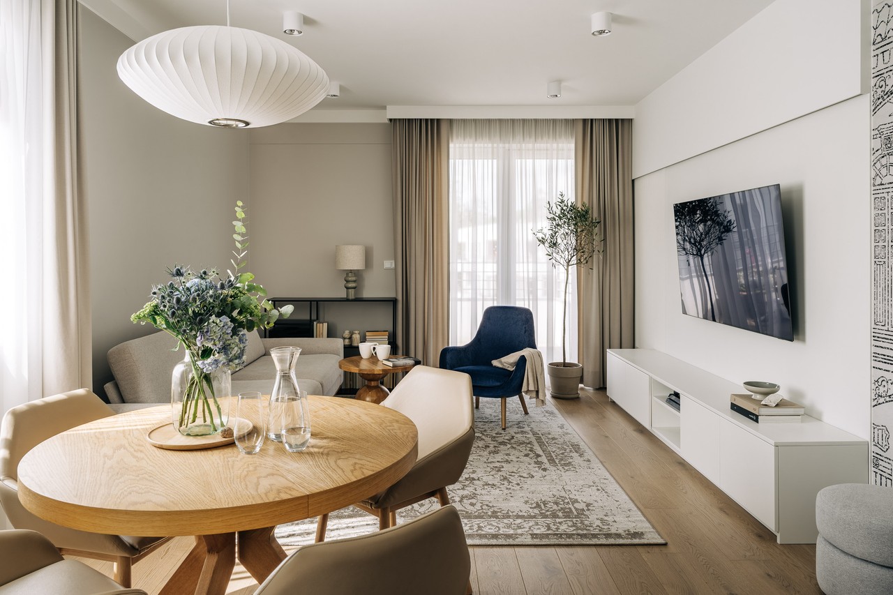 Elegant living room with large TV, wooden table and comfortable armchair.