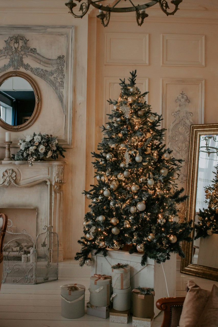 Elegancki salon z choinką udekorowaną złotymi ozdobami.