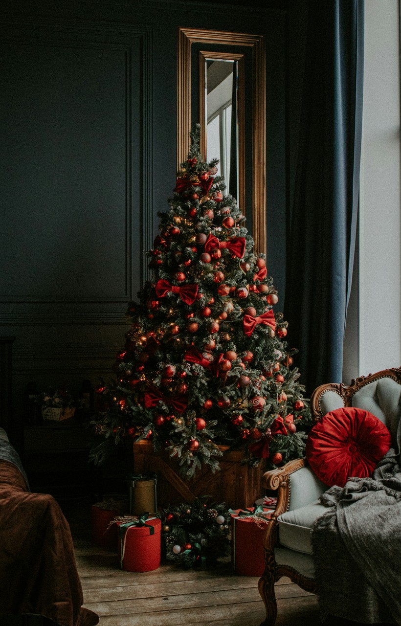 Świąteczne drzewko bogato ozdobione czerwonymi detalami w eleganckim wnętrzu.