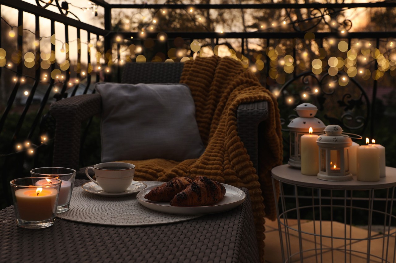 Przytulny balkon wieczorem z herbatą, rogalikami i świecami. Idealny relaks.