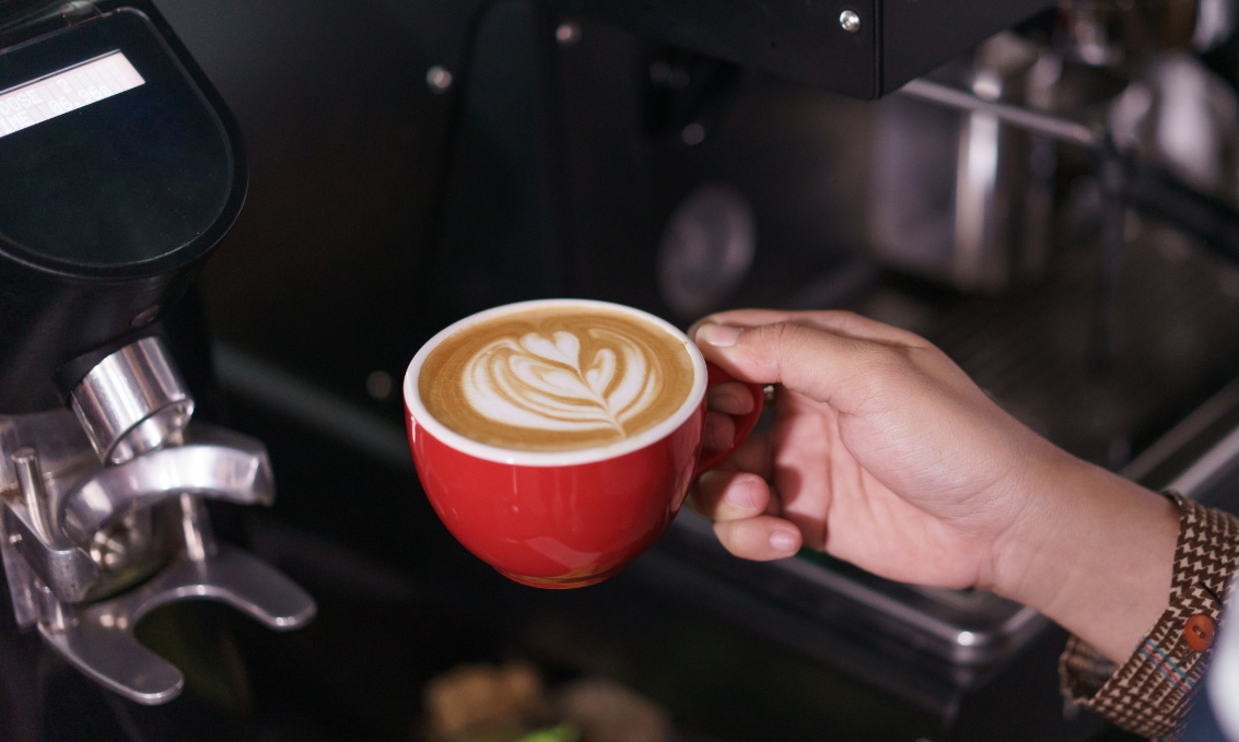 Kawa latte w czerwonej filiżance z wzorem latte art.