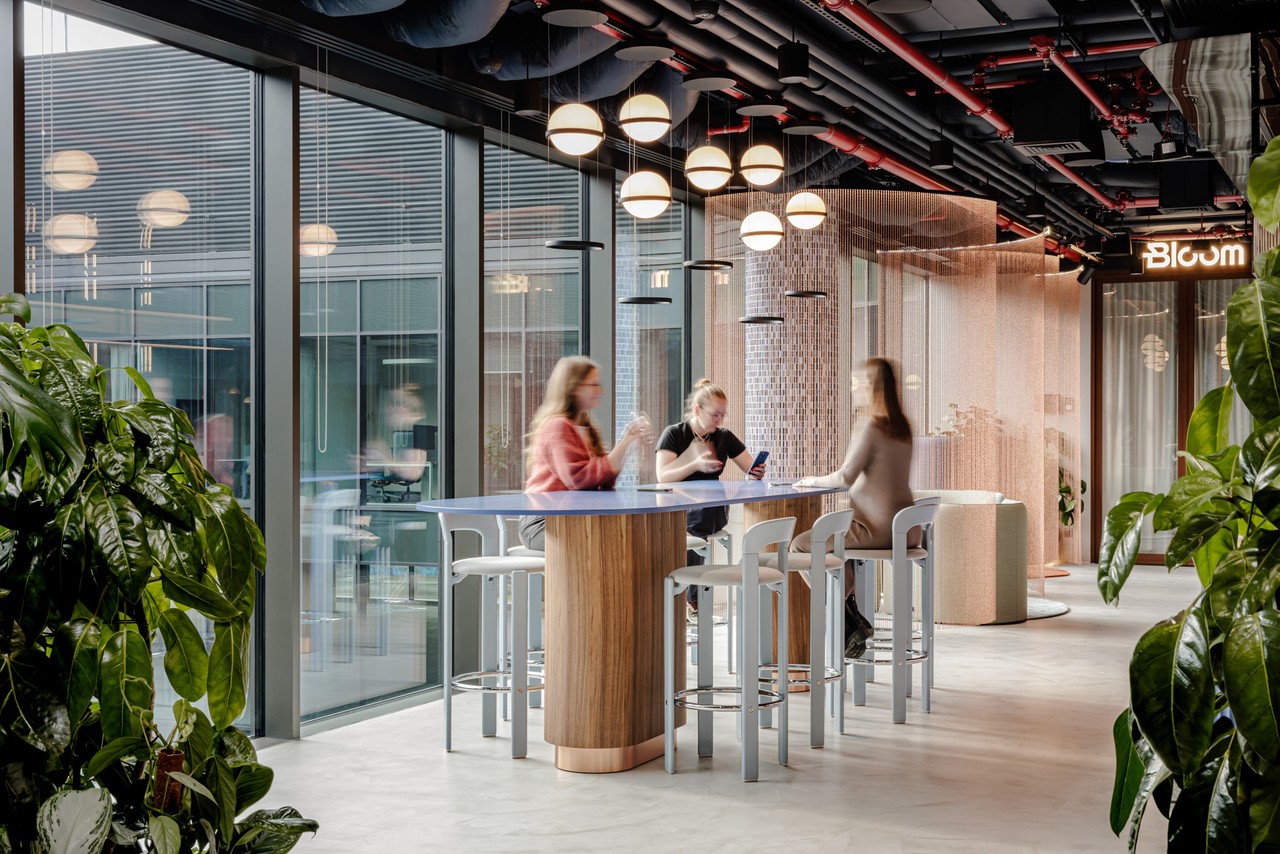 Nowoczesna przestrzeń coworkingowa z designerskim oświetleniem i roślinami.
