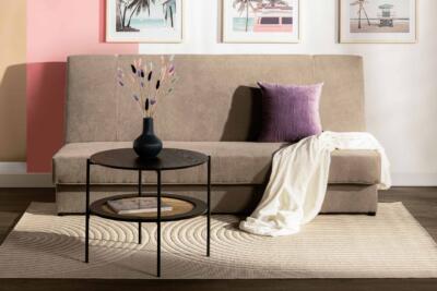 Nowoczesna sofa z fioletową poduszką, elegancki stolik i dekoracje.