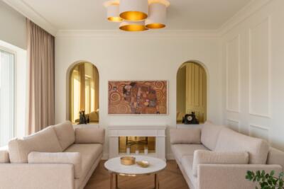 Przytulny salon z beżowymi sofami i designerskim oświetleniem.