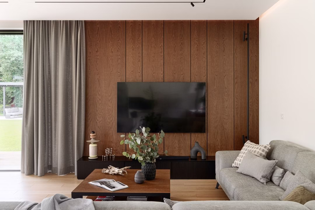 Elegancki salon z drewnianą ścianą i nowoczesnym telewizorem.