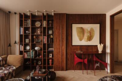Stylowy salon z drewnianą biblioteczką i nowoczesną sztuką.