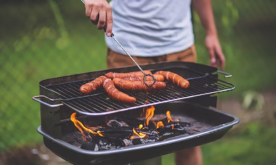 Grill w ogrodzie pełen smakowitych kiełbas na ogniu.