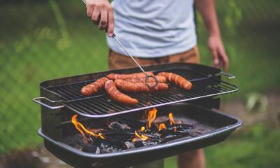 Grill w ogrodzie pełen smakowitych kiełbas na ogniu.