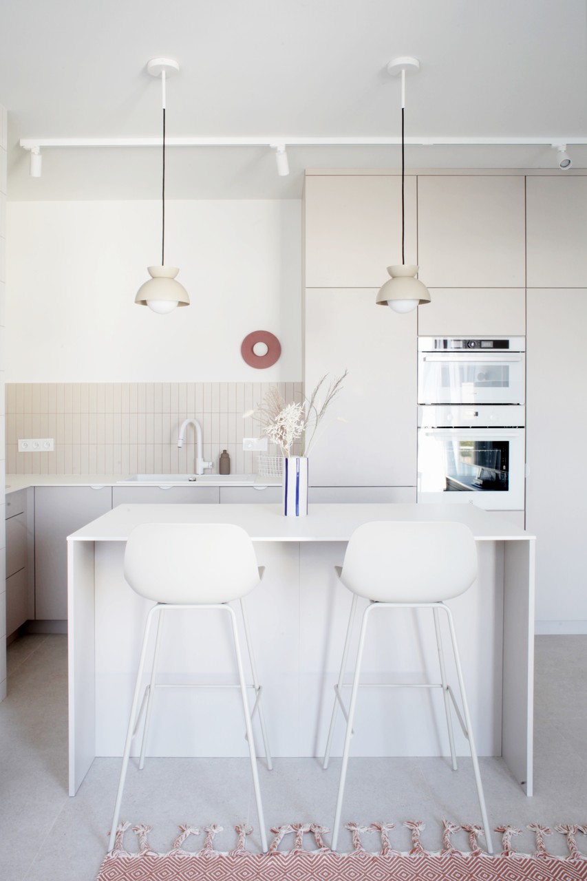 Nowoczesna kuchnia z białą wyspą i designerskimi lampami.