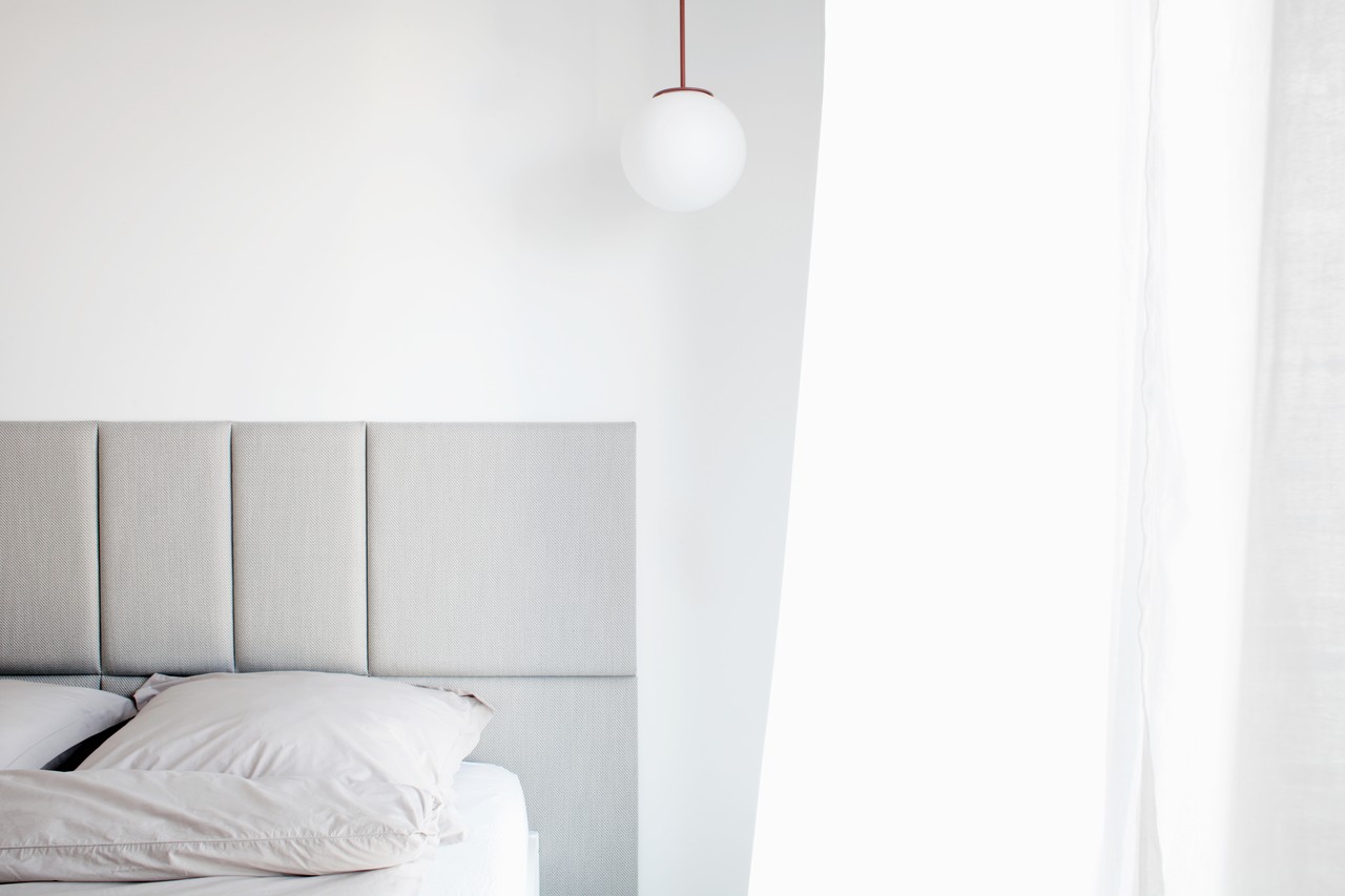 Minimalistyczna sypialnia: eleganckie łóżko, białe ściany, stylowa lampa.