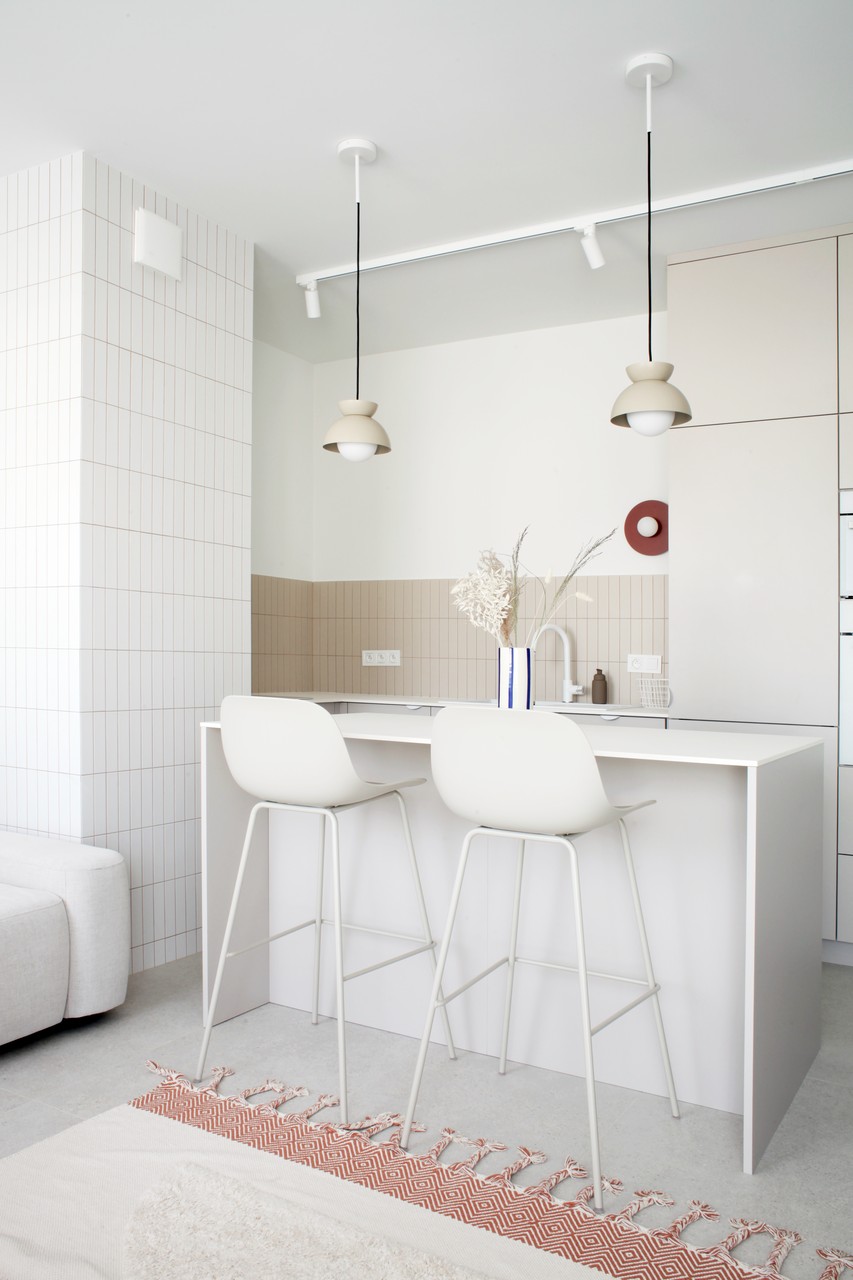 Nowoczesna kuchnia z eleganckim barem i designerskimi lampami.