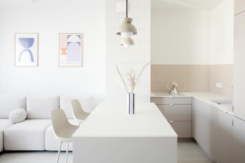 Minimalistyczna kuchnia z wyspą i designerskimi lampami.