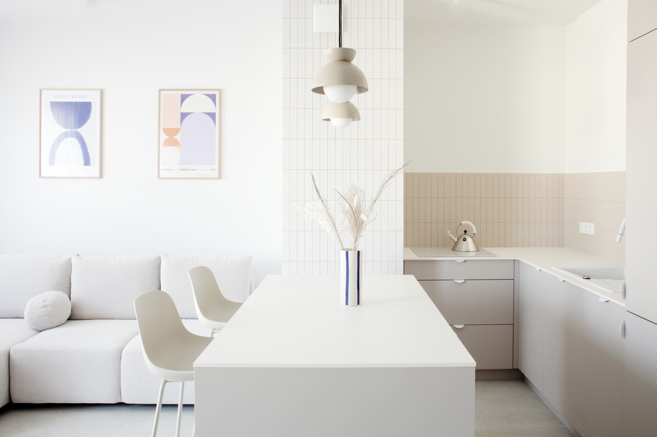Minimalistyczna kuchnia z wyspą i designerskimi lampami.