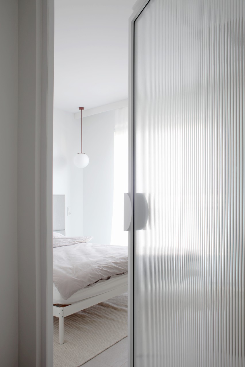 Minimalistyczna sypialnia z elegancką szklaną ścianą.