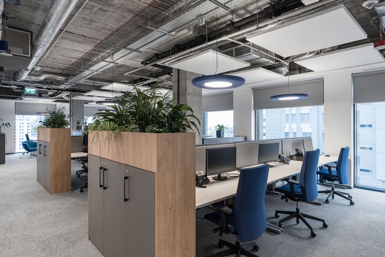 Nowoczesne biuro z roślinami i industrialnym sufitem.