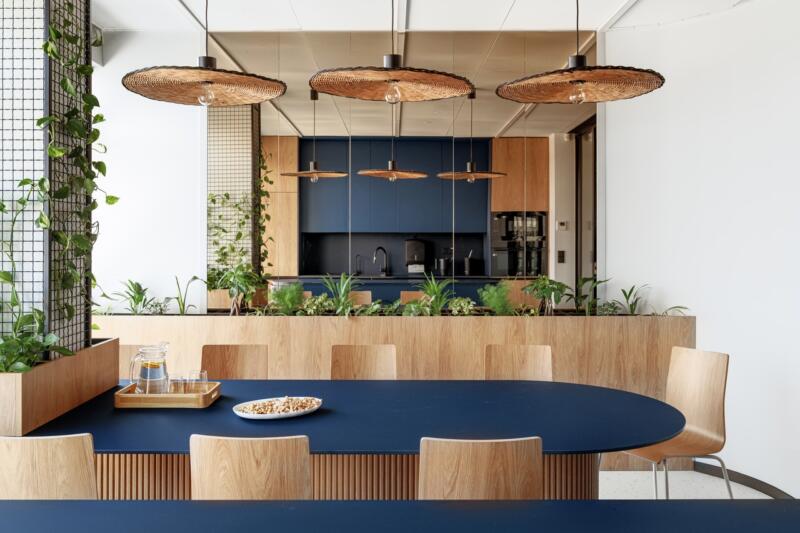 Nowoczesna kuchnia z drewnem, roślinami i designerskimi lampami.