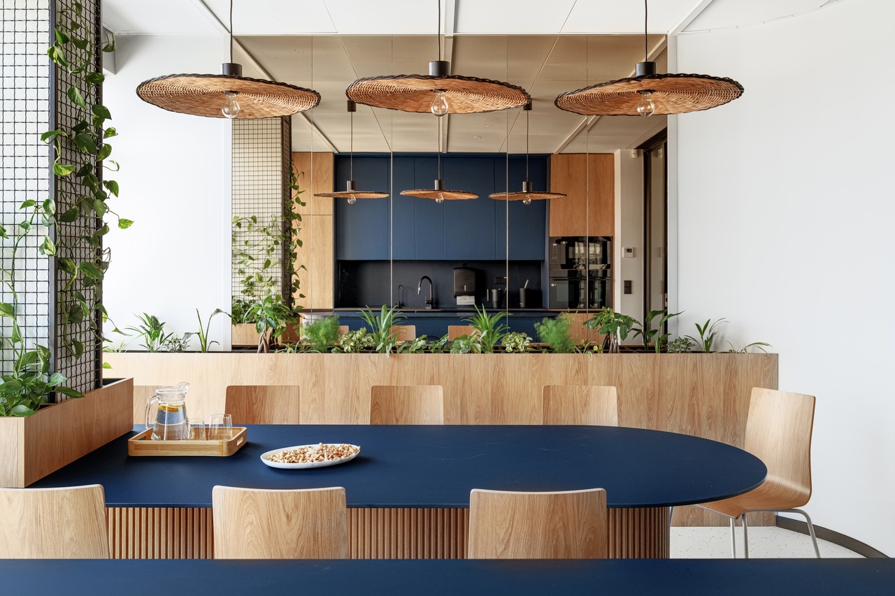 Nowoczesna kuchnia z drewnem, roślinami i designerskimi lampami.