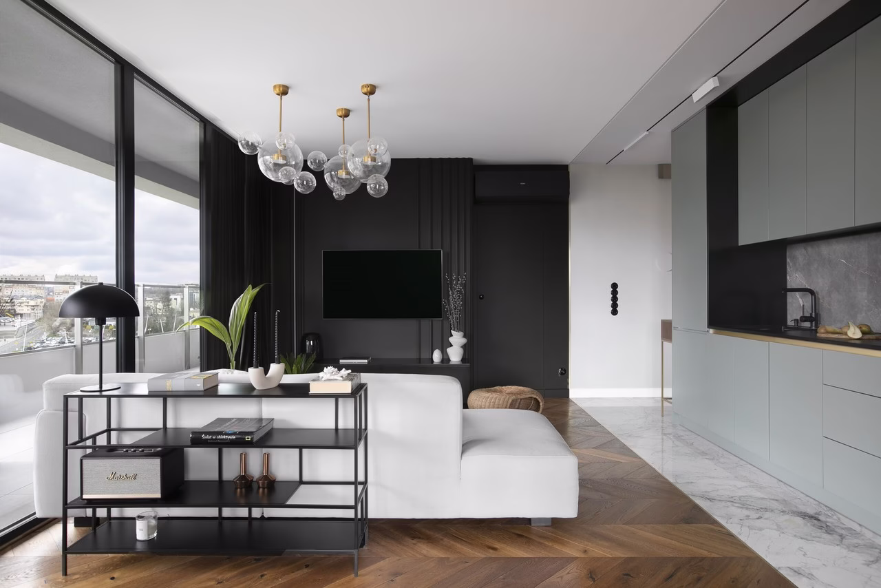 Nowoczesny salon z jasną sofą, kuchnią i designerskim oświetleniem.