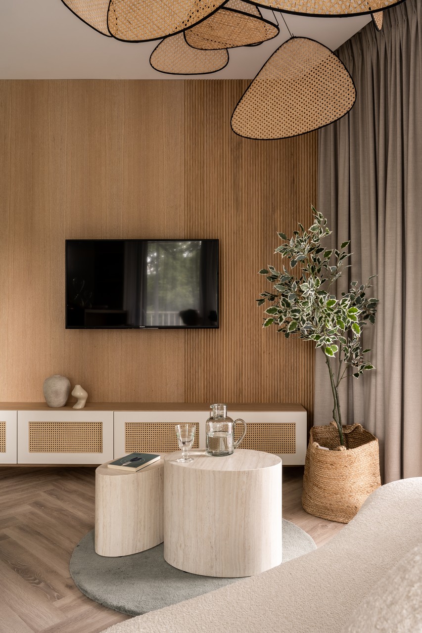 Nowoczesny salon z drewnianą ścianą, rośliną i minimalistycznymi meblami.