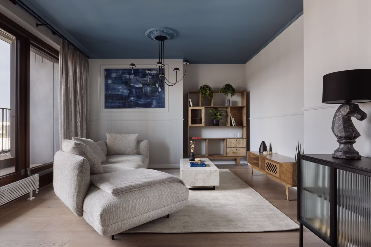 Nowoczesny salon z szarą sofą i drewnianymi regałami.