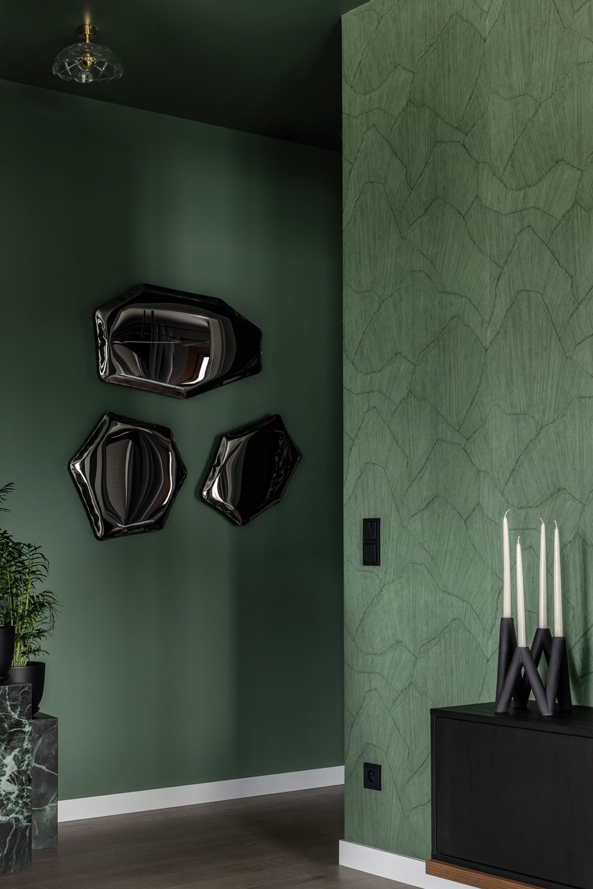 Zielona ściana z designerskimi lustrami i eleganckimi świecami.