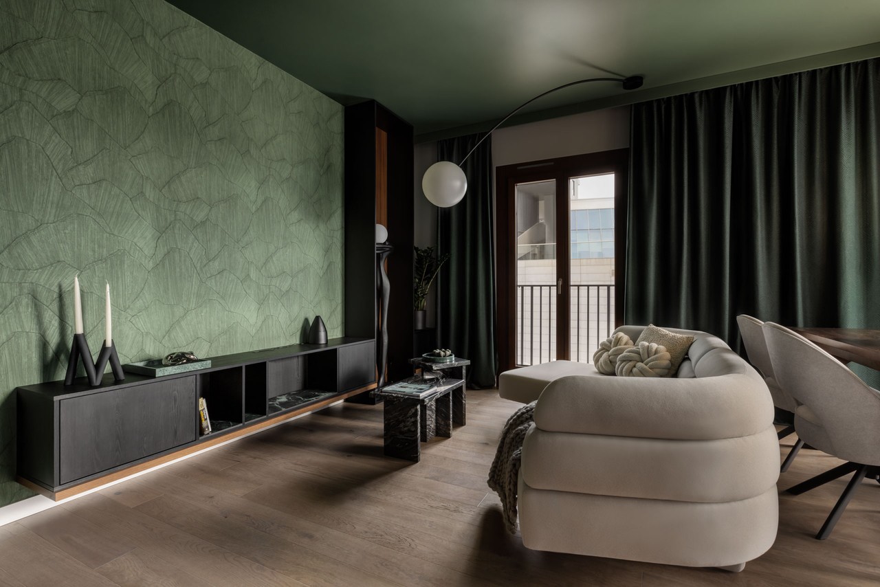 Nowoczesny salon z zieloną ścianą i stylową sofą.