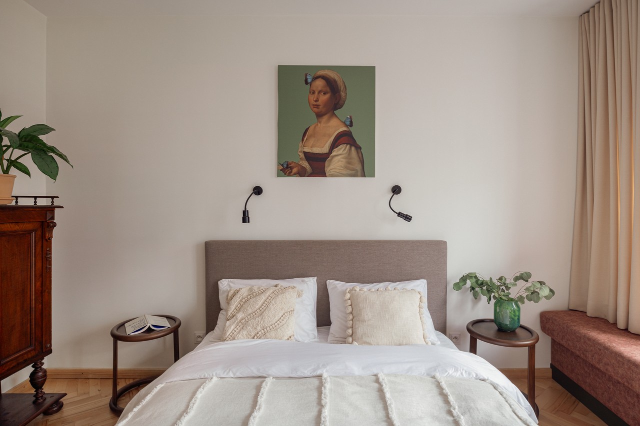 Przytulna sypialnia z eleganckim obrazem i stylowymi dodatkami.