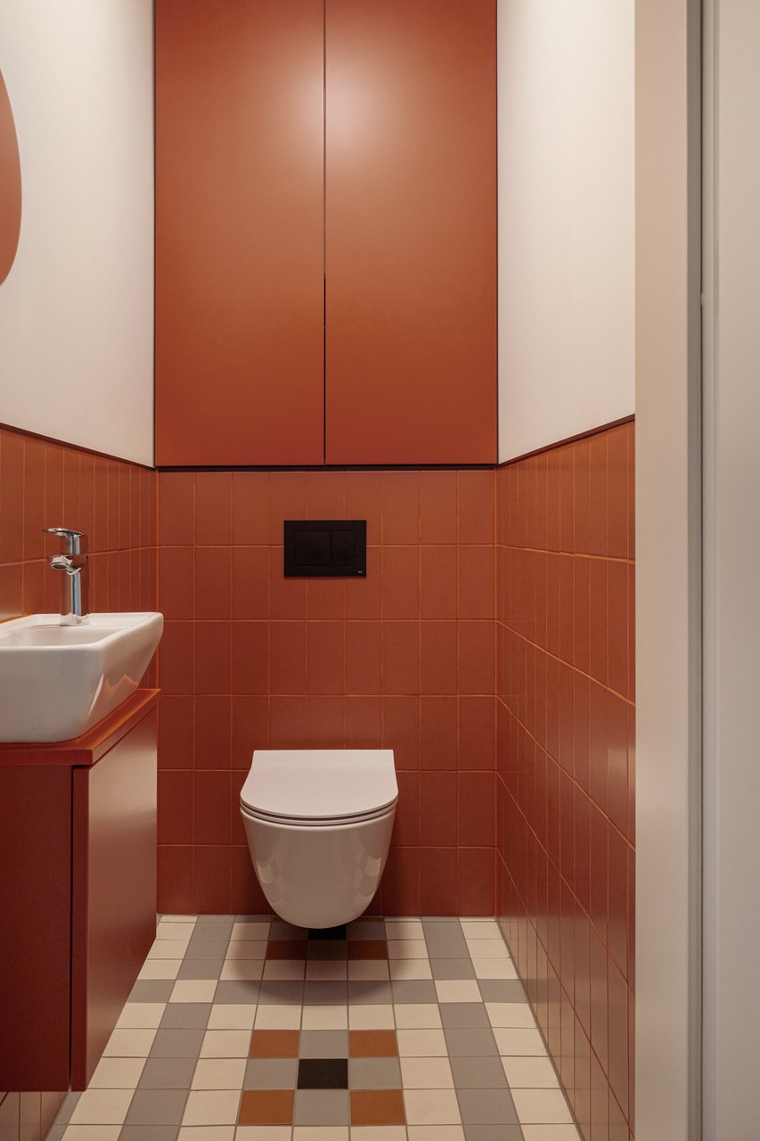 Ceglasty minimalizm i geometria w eleganckiej toalecie.