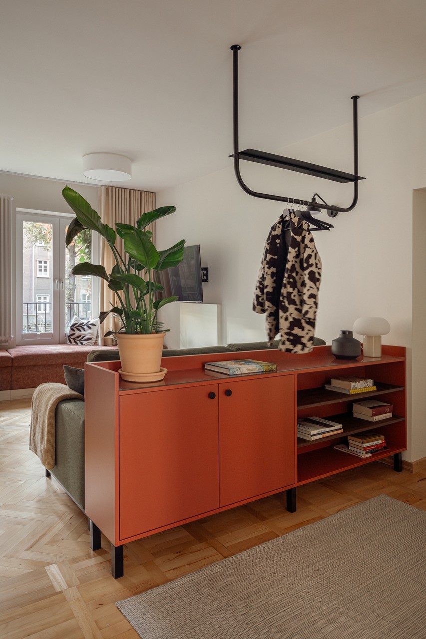 Stylowy salon z rośliną i nowoczesną szafką w ciepłych barwach.