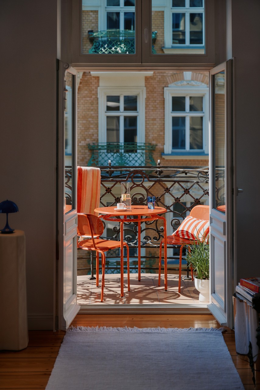 Przytulny balkon z pomarańczowymi detalami i klimatyczną aranżacją.