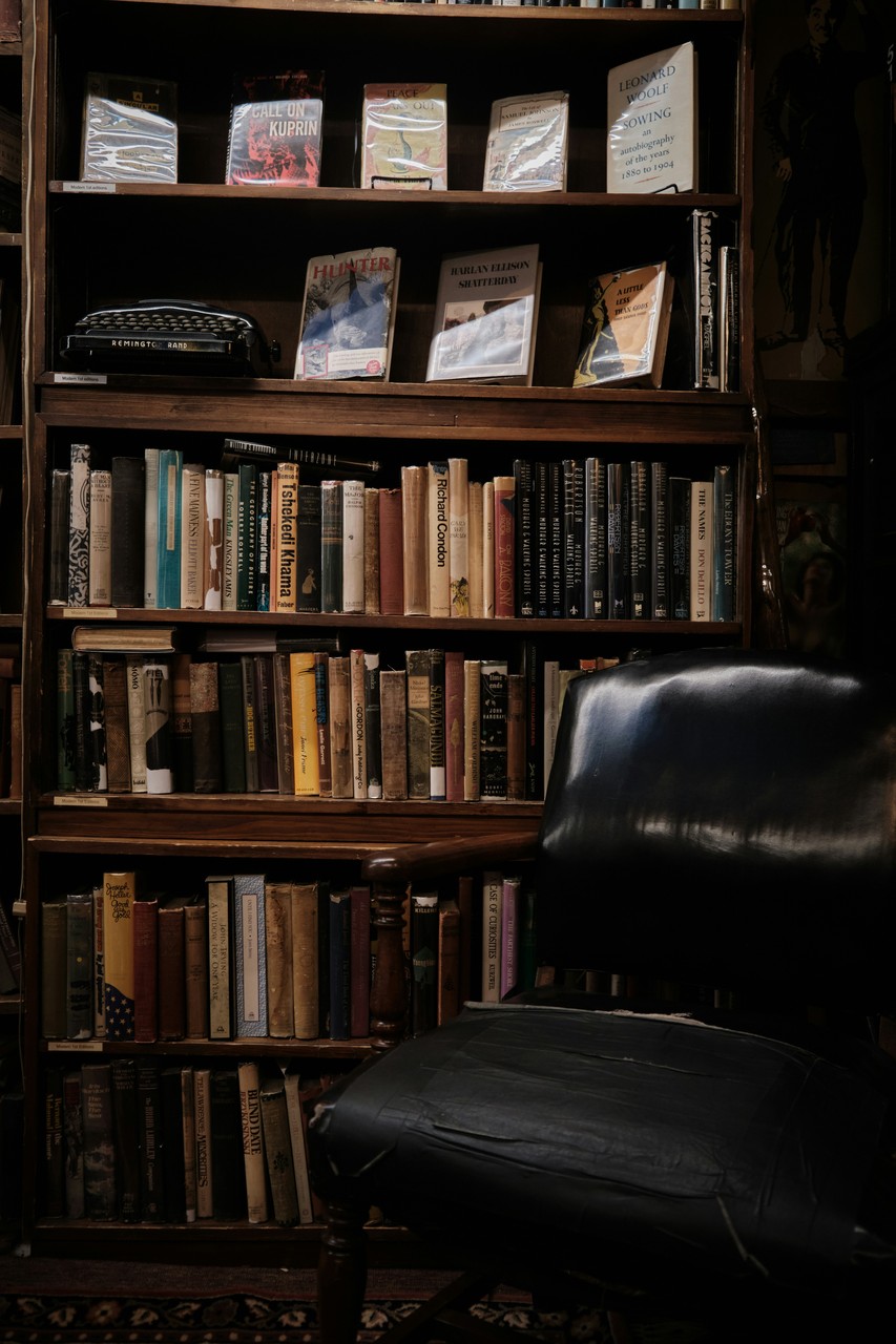 Biblioteka z regałem pełnym książek i stylowym krzesłem.