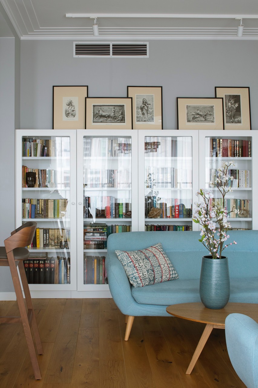 Modern library with white bookcases and blue armchair.