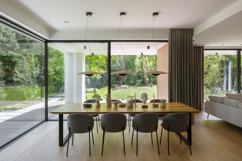Modern dining room with garden views through large windows.