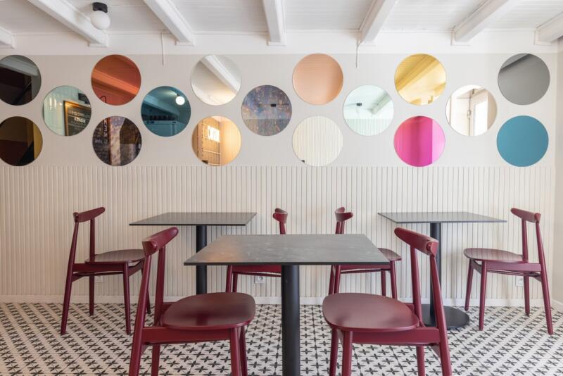 A modern café with colourful mirrors and burgundy chairs.