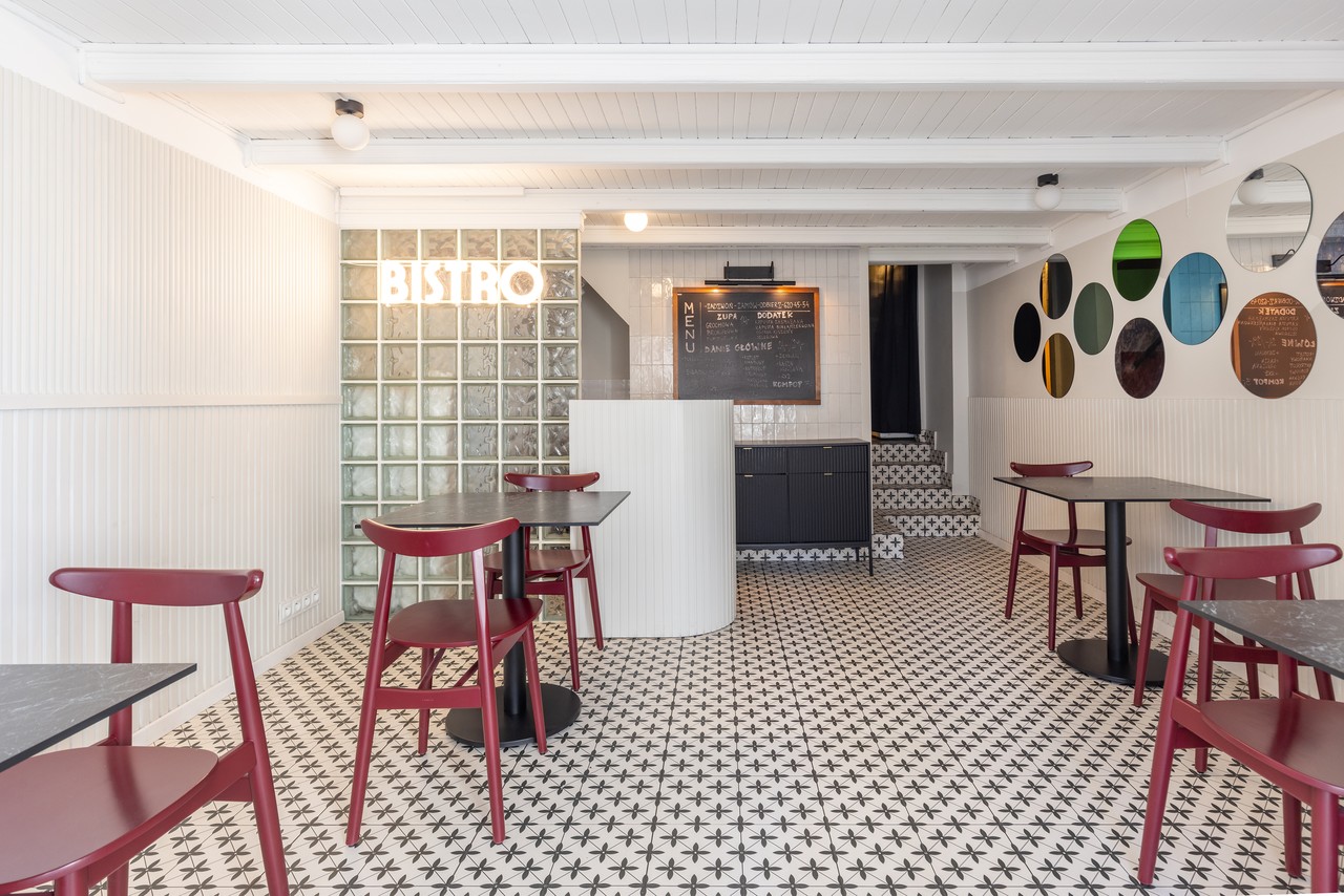 A stylish bistro with red chairs and a geometric floor.