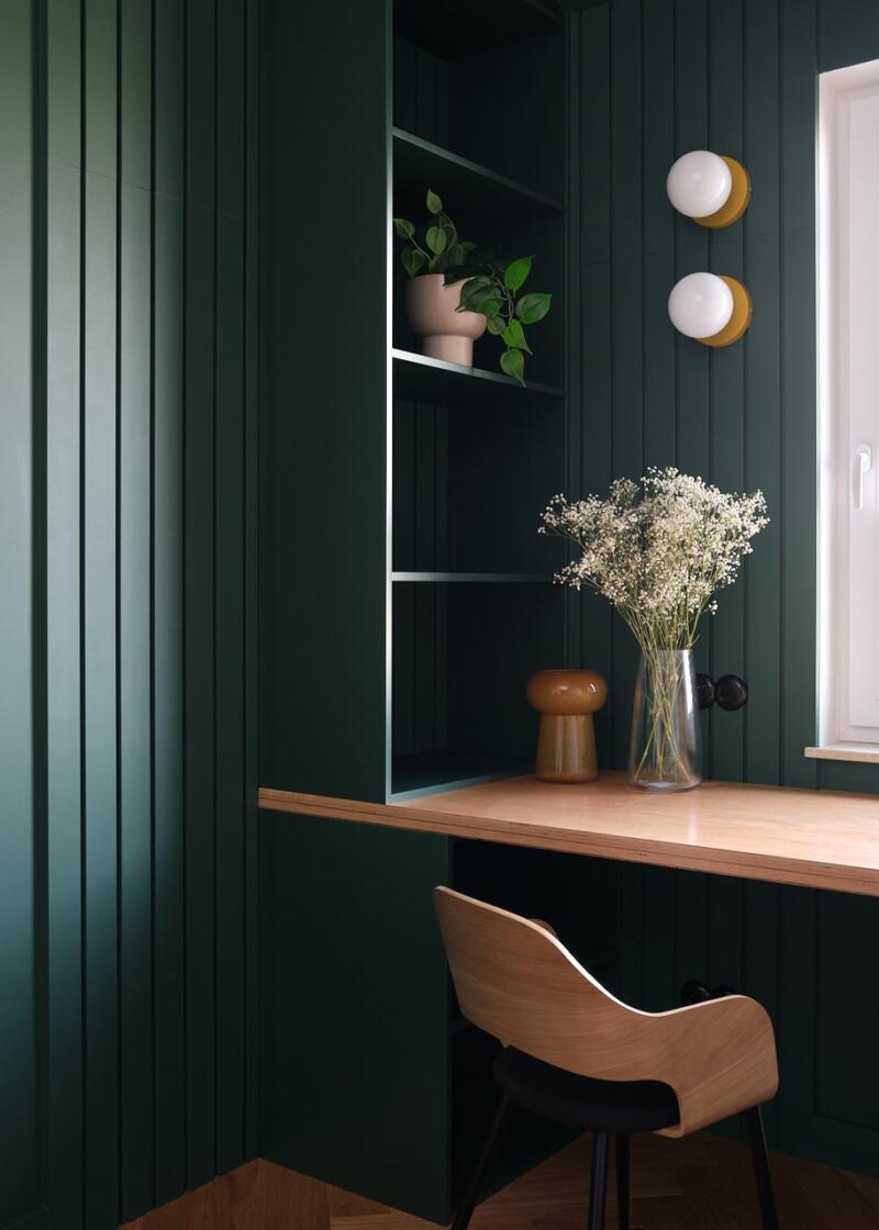 Green wall, wooden desk and elegant accessories in the study.