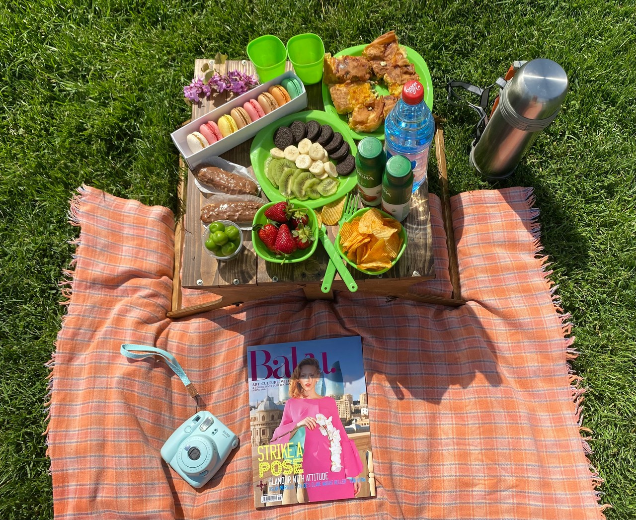 Piknikowy zestaw na trawie z przekąskami i magazynem modowym.