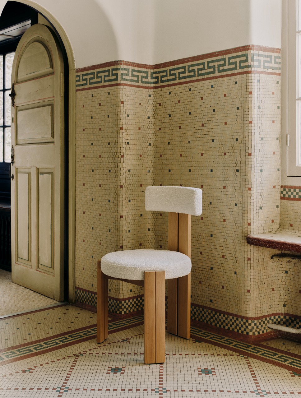 Krzesło designerskie w tle mozaikowej ściany z geometrycznym wzorem.