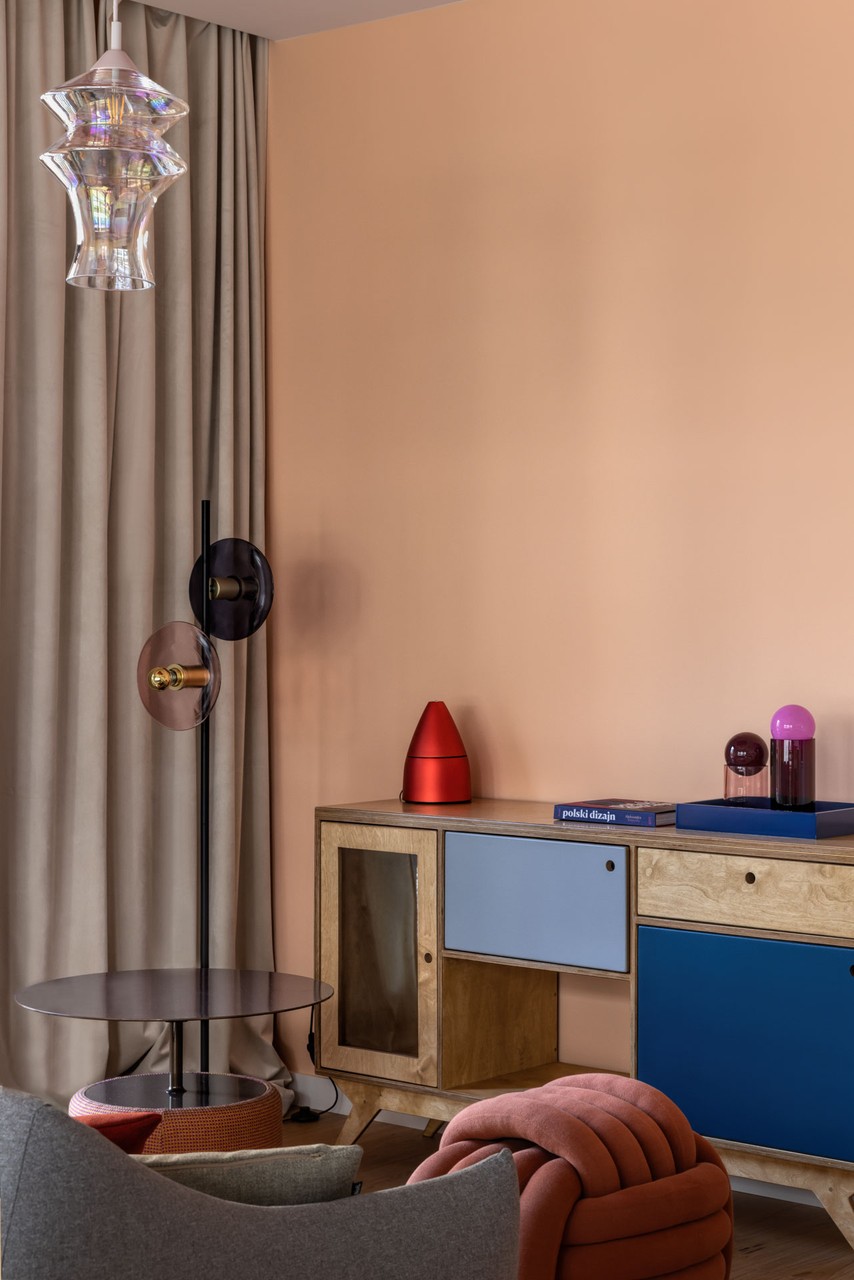 Designerski salon z kolorową komodą i nowoczesnym oświetleniem.